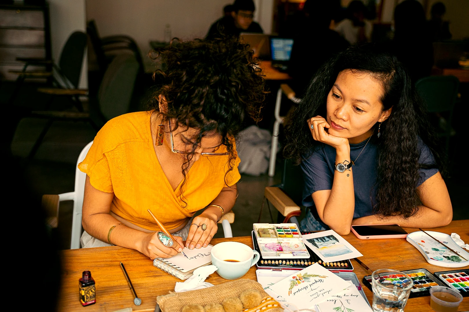 Two women at a table, deep in creative work together—The Salon circle